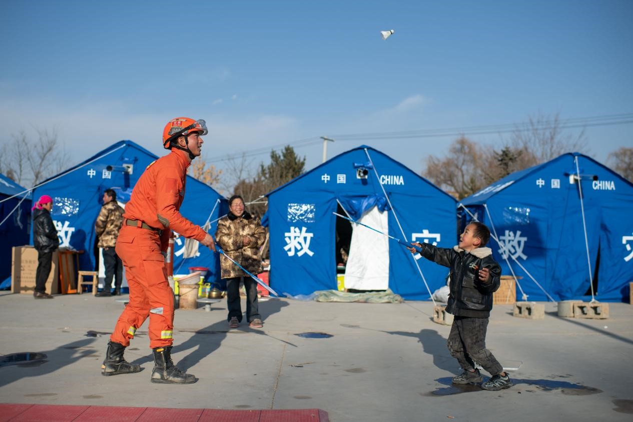 12月21日，在積石山縣石塬鎮(zhèn)石塬村安置點(diǎn)，消防救援人員忙里偷閑教小朋友打羽毛球。人民網(wǎng)記者 翁奇羽攝